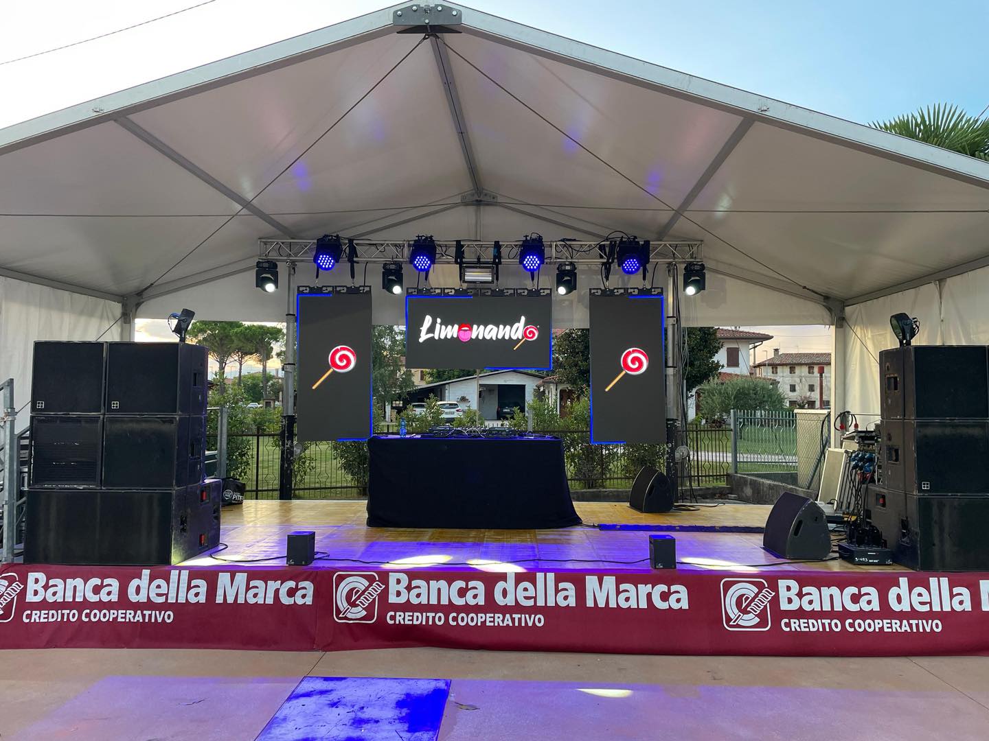 Palco di Limonando sotto un tendone: tre LED wall, fari e casse ai lati della consolle